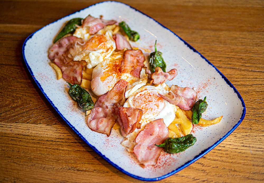 Huevos rotos (soft yolk eggs) with bacon and small green padron peppers